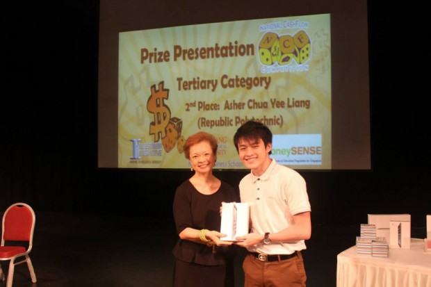 ALL SMILES: 1st runner up Asher Chua (right) as he receives his prize from a NCF 2014 organiser. Photo (Courtesy of National Cash-flow Competion Facebook page)