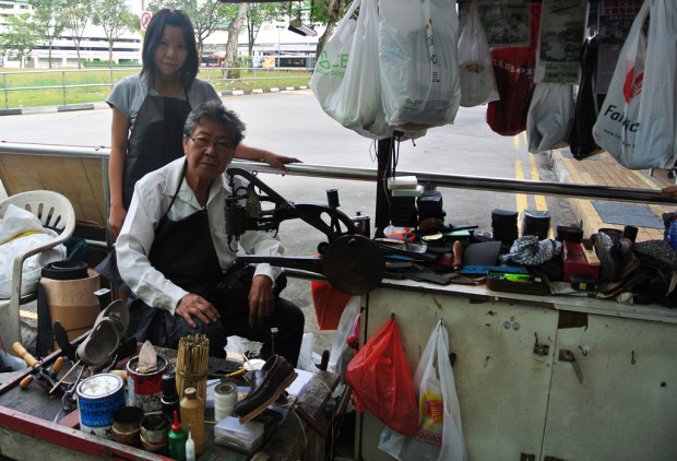 FATHER-DAUGHTER DUO: In their corner at the Yishun bus interchange, they fix broken soles for a living. (PHOTO: Cheryl Wong)