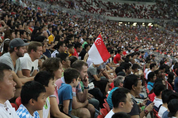 FIRST OF MANY: A solitary flag among the crowd. Perhaps, when Singapore regains the Kallang Roar, we might see a whole stadium waving their flags in unison. (Photo: M. Shanjayan))