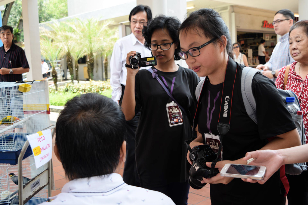TELL ME A STORY: Students from Tanjong Katong Girls' School interview the owner of a bird shop in Ang Mo Kio on the second day of the competition. (Photo: Iskandar Rossali)