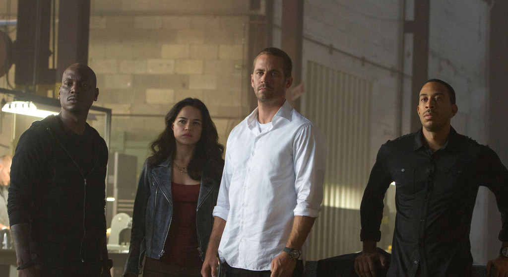 ONE LAST HURRAH: The late Paul Walker (2nd R), who died in a car crash in late 2013 while the movie was being made, appears with co-stars Michelle Rodriguez, Chris “Ludacris” Bridges and Tyrese Gibson (L) in a scene from Furious 7. (Photo: http://www.fastandfurious7film.com)