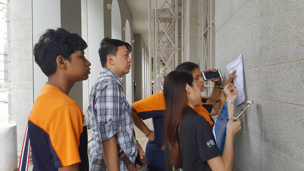 GET YOUR HEAD IN THE GAME: Students from Fajar Secondary School took a quick break to reexamine their clues before moving on to their next destination. (Photo: Yeow Chin Chin)