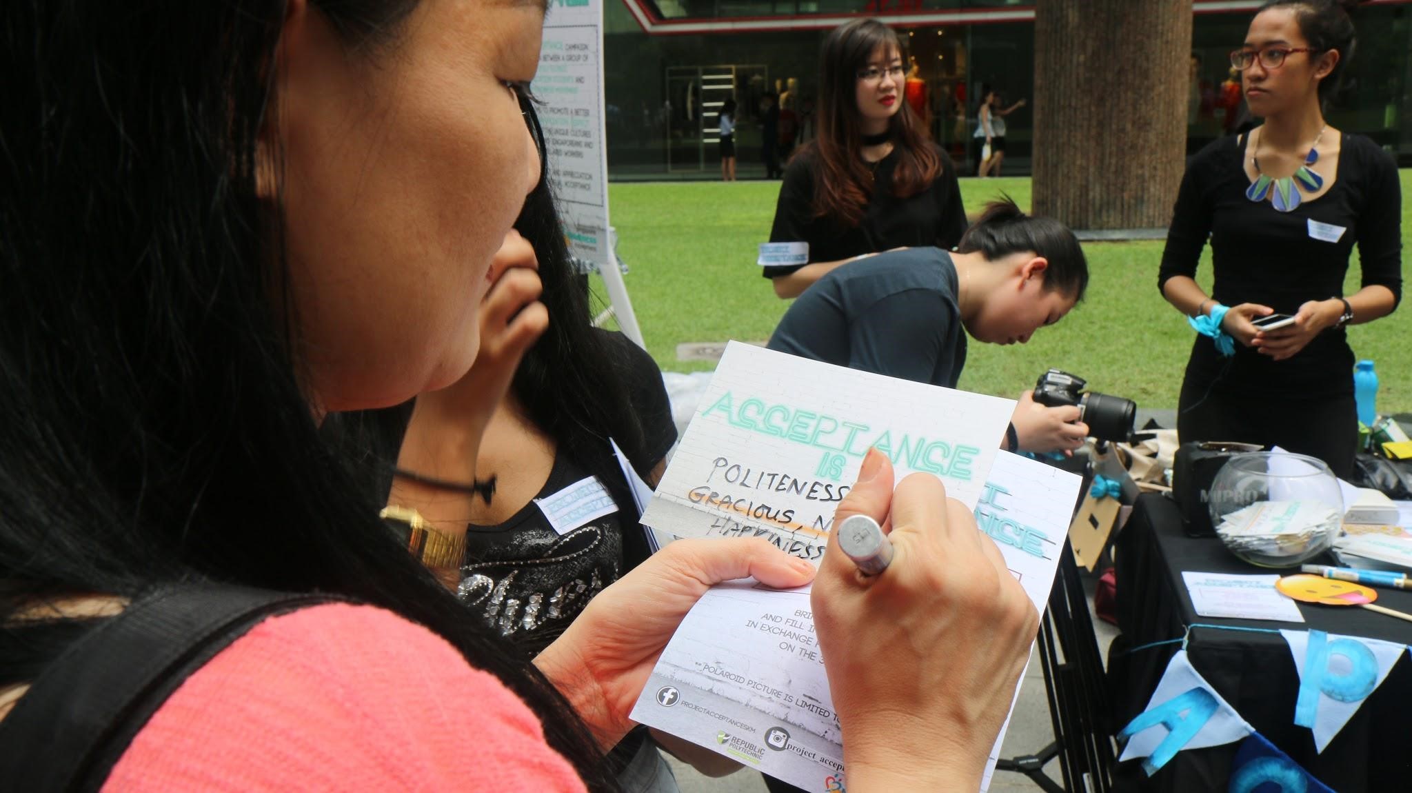 REFLECT: A booth was set up at Zoysia Green, Raffles Place Park on Aug 3, 2016 to encourage the lunch crowd at Zoysia Green, to reflect on and pen down what acceptance means to them in the context of social integration on a Acceptance card. (Photo: Joan L Koh Jia Min)